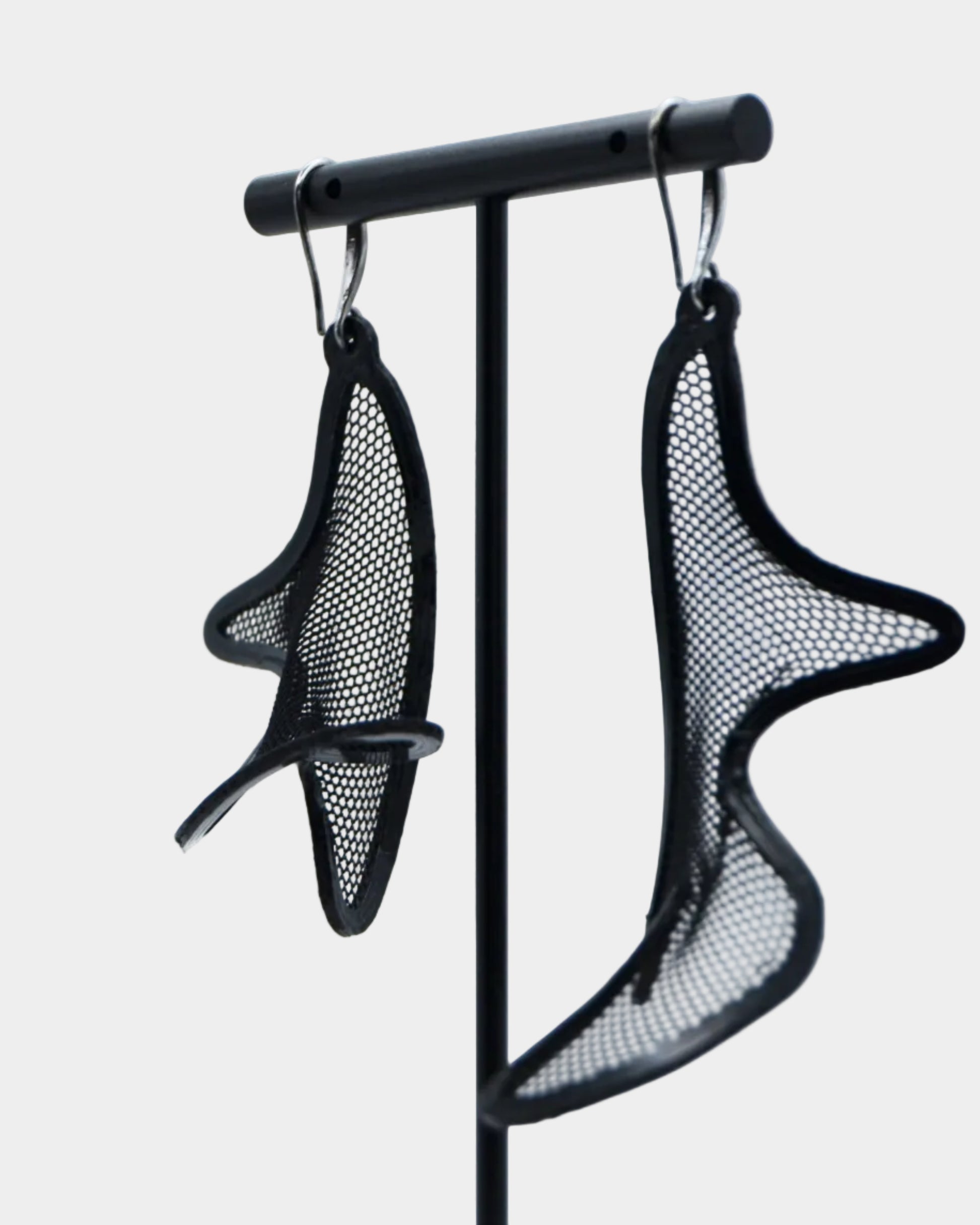 Black mesh earrings on a stand against a white background