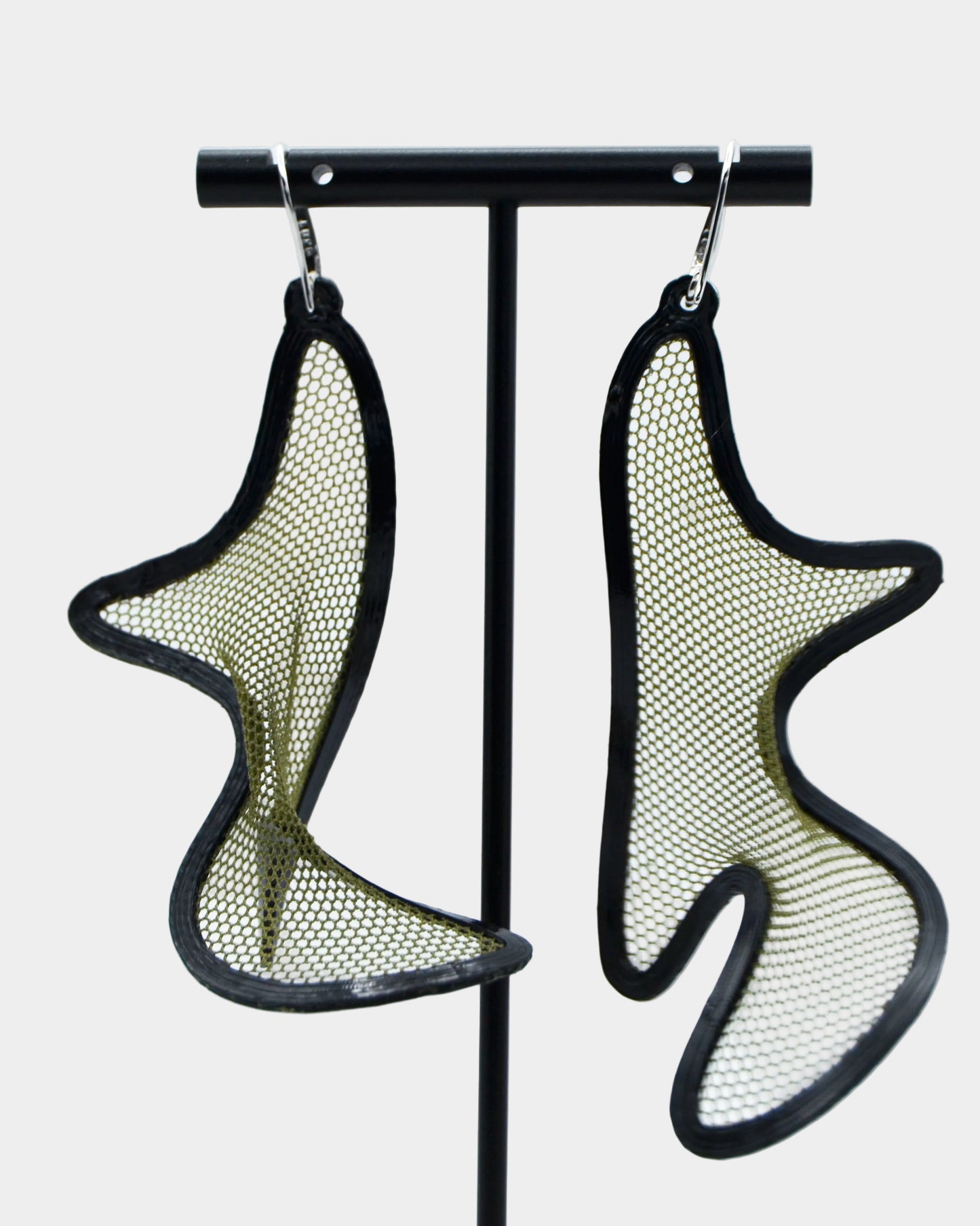 Pair of green mesh earrings on a stand against a white background