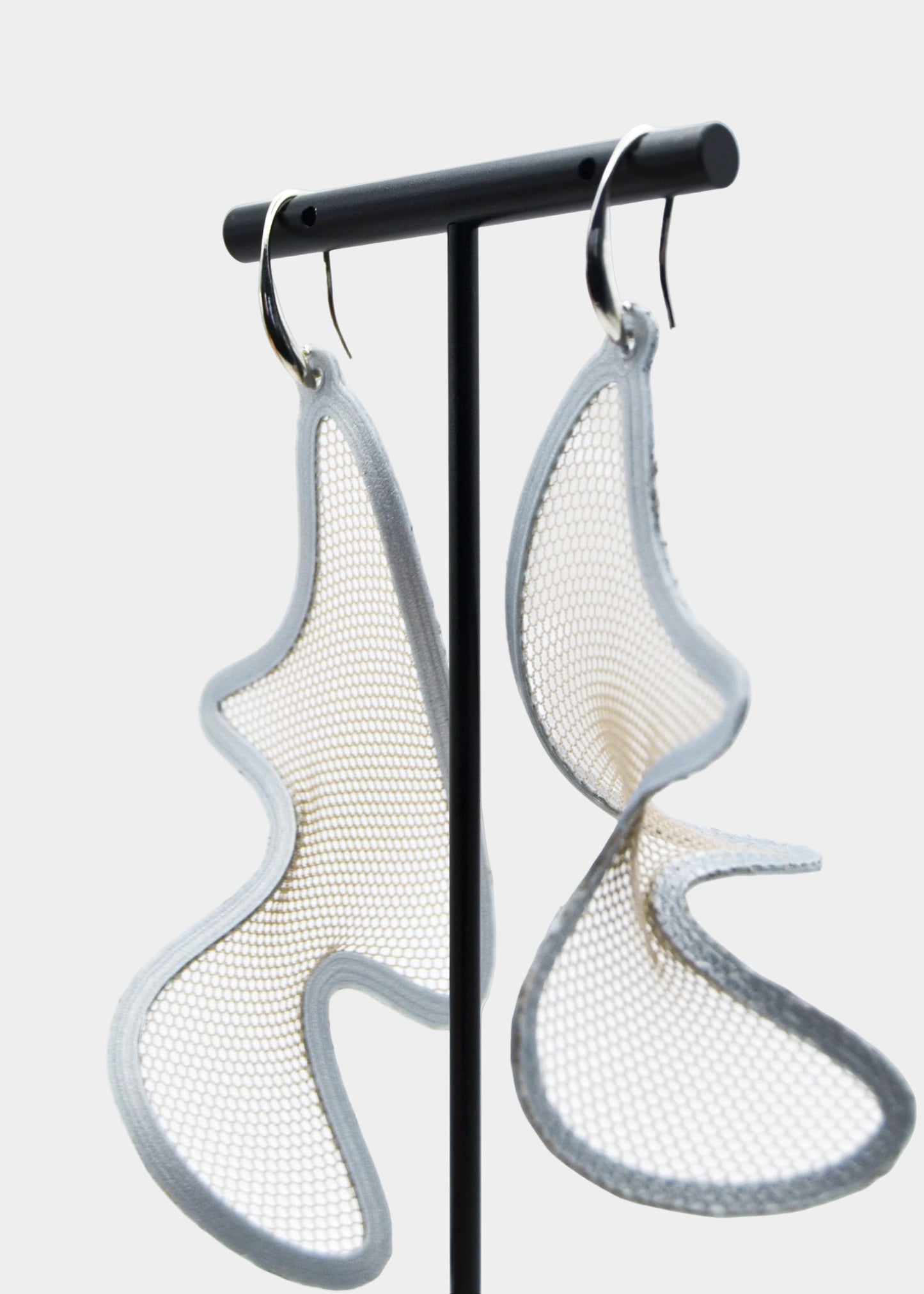 Pair of earrings on a stand against a white background